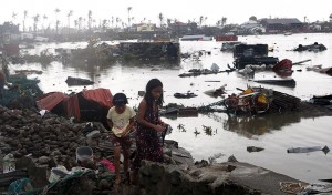 Residents walk near vehicles and debris floating on a river after Super Typhoon Haiyan devastated Tacloban city in central Philippines