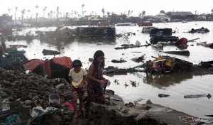 Residents walk near vehicles and debris floating on a river after Super Typhoon Haiyan devastated Tacloban city in central Philippines